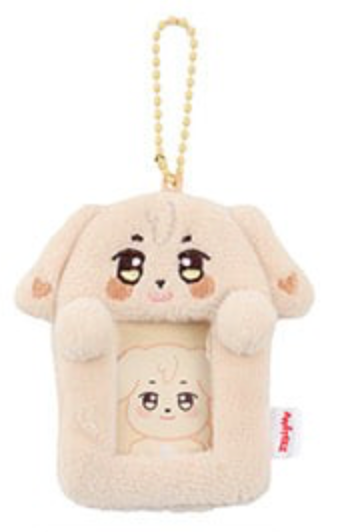 A plush dog-shaped phone pouch or keychain in a soft cream color, featuring a cartoon face on the front, a small character window, and a gold bead chain at the top.