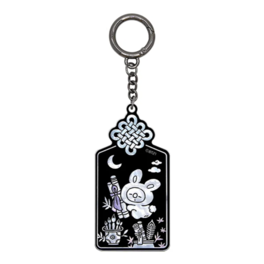 A black and silver keychain featuring a white cartoon bunny, a crescent moon, clouds, and plant details, suspended from a silver metal ring on a plain white background.