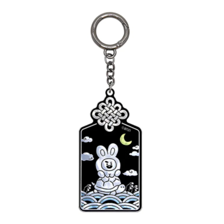 A metal keychain featuring a black enamel pendant with a white rabbit illustration, clouds, a crescent moon, and blue wave patterns, suspended from a silver chain and key ring on a white background.