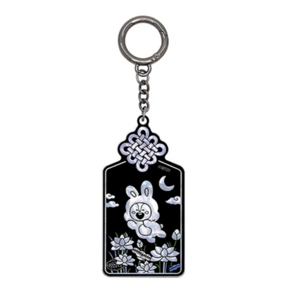A black and silver keychain featuring a white cartoon bunny, a crescent moon, clouds, and floral details, suspended from a silver metal ring on a plain white background.