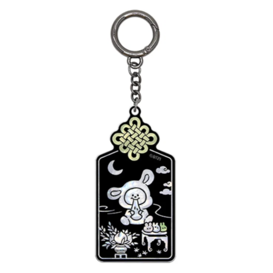 A black enamel keychain featuring a cartoon rabbit sitting with a crescent moon, clouds, and a gold-toned Chinese knot at the top, attached to a silver metal ring.