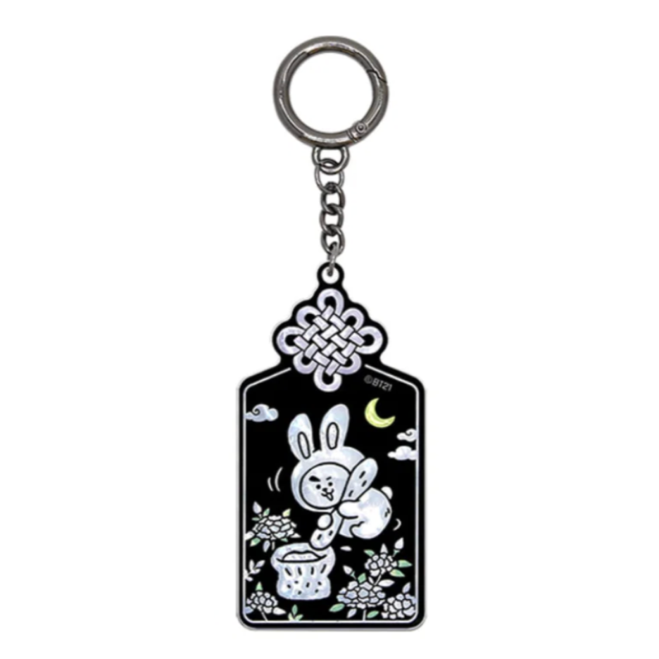A black and silver keychain featuring a white cartoon bunny, a crescent moon, clouds, and floral details, suspended from a silver metal ring on a plain white background.