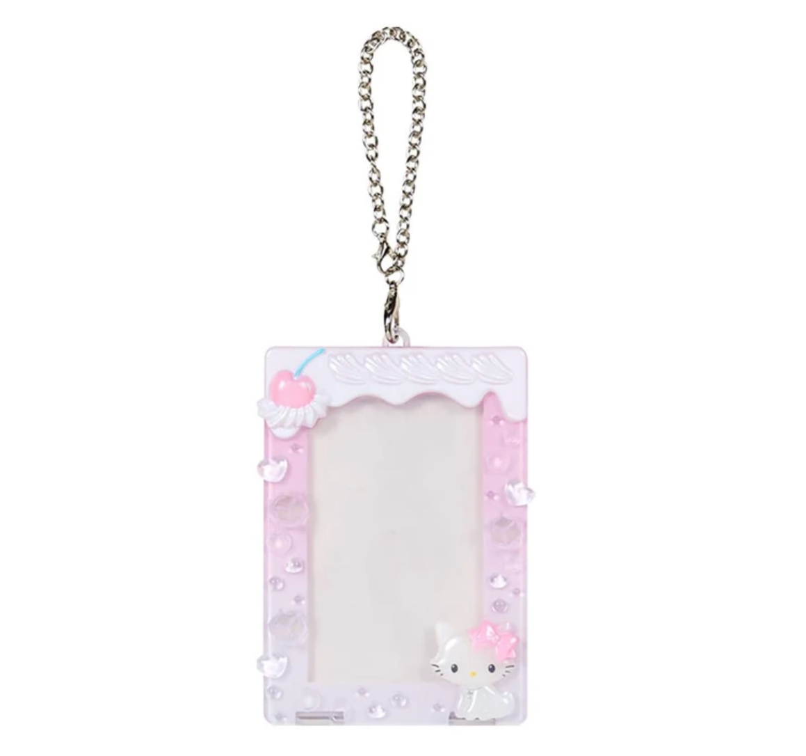 A cute pink and white decorative picture frame keychain with a silver metal chain, featuring a Hello Kitty character design and 3D cherries on a white background.