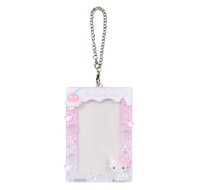 A cute pink and white decorative picture frame keychain with a silver metal chain, featuring a Hello Kitty character design and 3D cherries on a white background.
