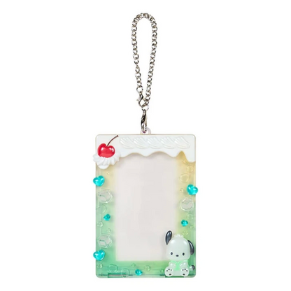 A rectangular acrylic keychain card holder with a silver chain, decorated with a white top border, a red cherry, turquoise heart charms, a small white cartoon dog at the bottom, and a light green gradient base.