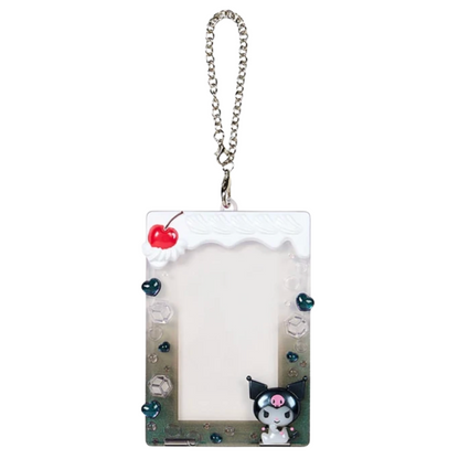 A Sanrio Kuromi acrylic photo frame keychain with a silver chain, featuring a white top border with a red cherry, a gradient body transitioning from white to green and blue, and a Kuromi character at the bottom right.