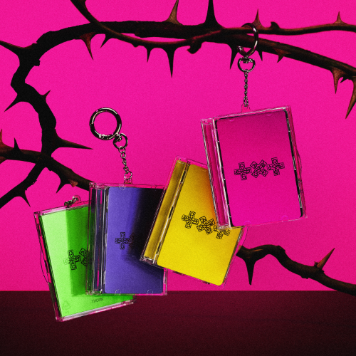 Colorful transparent keychains with cross designs on a pink background with black thorns.